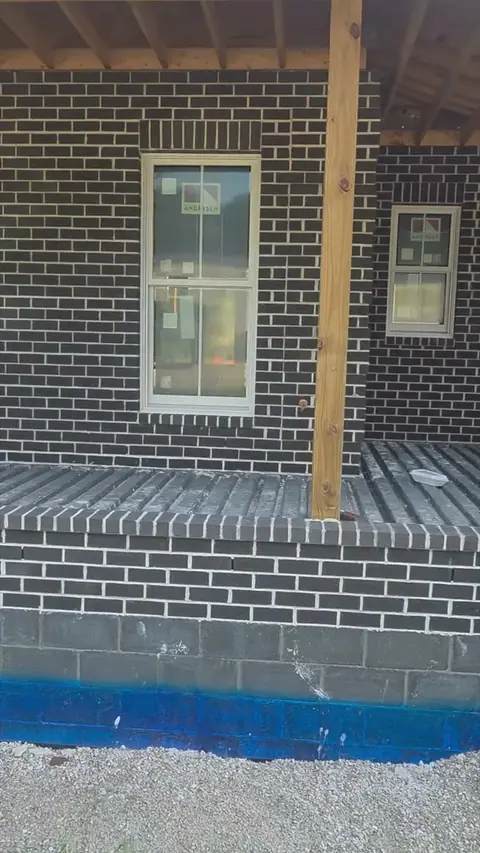 Dark brick around a window, with a soldier-course header and brick sill above a block foundation.
