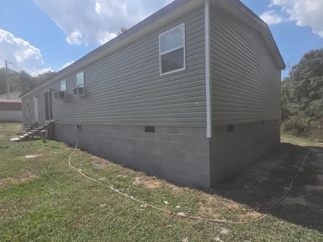 A long house sitting on continuous gray block underpinning with vents spaced along the wall.