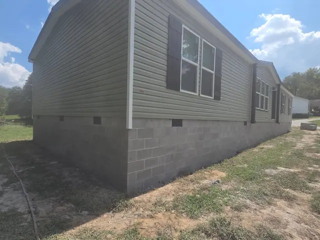 Continuous block underpinning with foundation vents below a sided house.